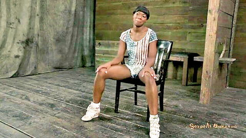 Seductive ebony woman in patriotic flag outfit sitting on chair, teasing pose