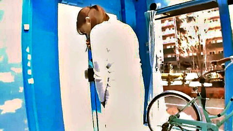 Japanese amateur in white dress bending near bike saddle, urban tease