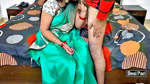 Desi Indian woman in green saree grabs man's thigh near crotch in red shorts on bed