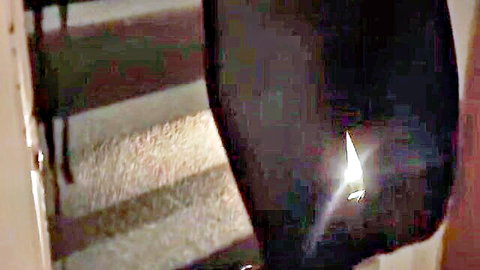 BDSM woman in black corset restrained on chair in dim light