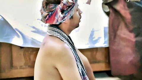 Shirtless South Asian man in colorful turban and beaded necklace sitting bare-chested