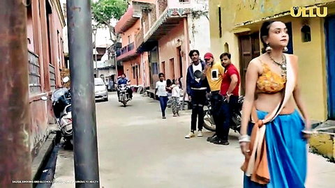 Indian woman in yellow saree top and blue skirt walks teasingly in colorful village street