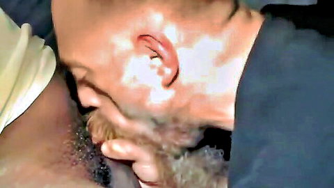 Closeup of bald bearded white man face buried in black guy's hairy crotch sucking balls