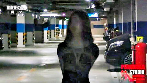 Young Chinese girl in tight black dress, tied up in BDSM scene, walking in carpark
