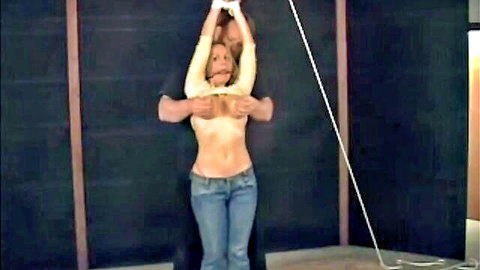 Topless bound woman groped by man in BDSM teaser, exposed breasts and rope restraint