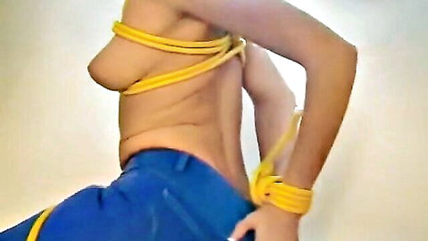 Asian woman bound in yellow ropes exposing breasts in denim BDSM scene