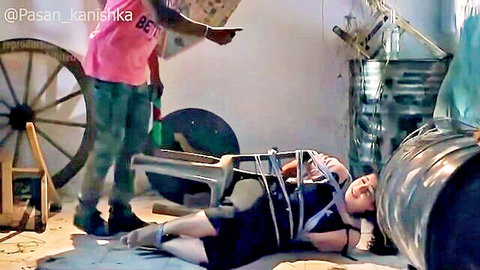 Asian woman tied up in black dress with man dominating in BDSM scene