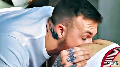 William Seed's tattooed hunk kisses muscular man's neck in gay threesome