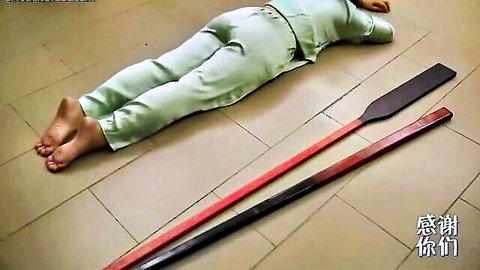 Chinese girl in green outfit prone for ancient BDSM paddling punishment