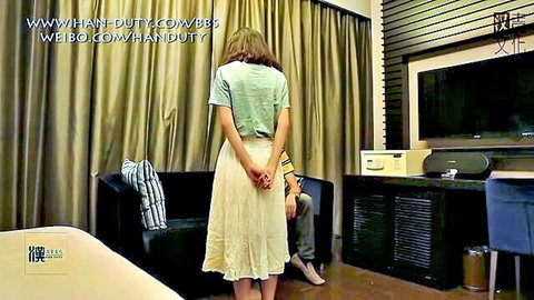 Chinese babe in skirt with hands behind back in BDSM setup