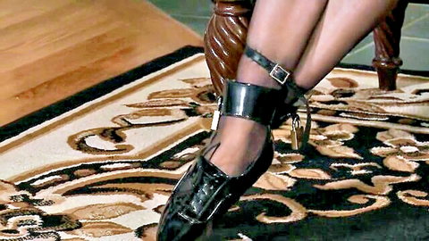Shiny latex-clad legs bound in locked cuffs for BDSM lezdom tease