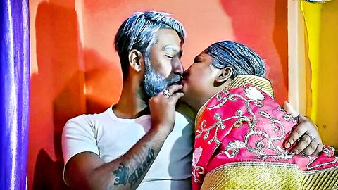 Older Desi Indian couple passionately kissing, housewife in pink saree