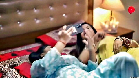 Two busty Indian brunettes in saree and salwar puckering lips for playful selfie kiss on bed