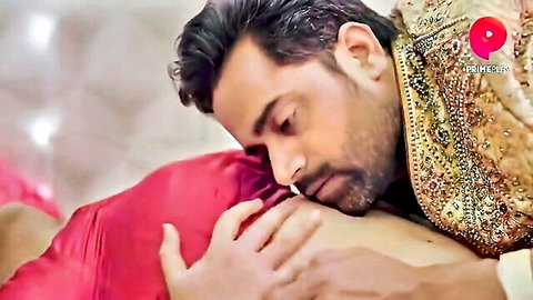Indian man passionately kissing brunette woman's neck while embracing her in red lingerie on bed