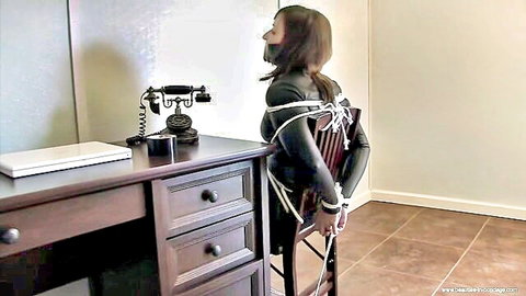 Bound brunette in latex gagged and restrained in BDSM capture scene