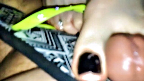 Close-up of woman's foot in green flip flops giving shoejob to hard cock