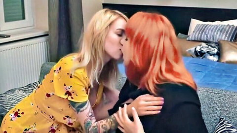 Tattooed blonde in yellow floral dress passionately kisses redhead lesbian on bed