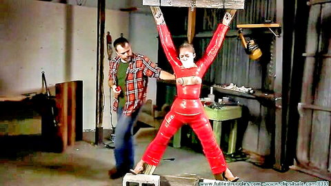 Bound milf in red latex suit dominated by man in intense BDSM scene