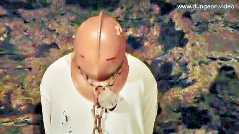 Masked male slave in chains and collar in BDSM dungeon