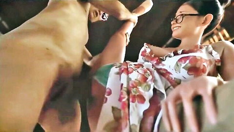 Smiling Asian woman in glasses and floral dress gets her pussy penetrated by naked man's big cock from behind