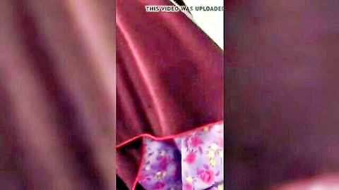 Malay woman in long purple tudung lifting to reveal pink floral panties