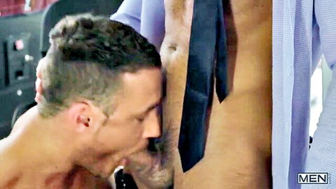 Two fit office men in suits, one kneeling to kiss exposed crotch at work