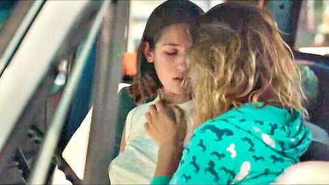 Two young women in intimate embrace on bus in hot movie scene