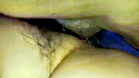 Closeup of hairy mature pussy with blue gloved finger inserted deep inside