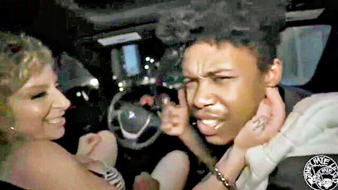 Smiling blonde babe flirts with black guy grimacing tongue out in car