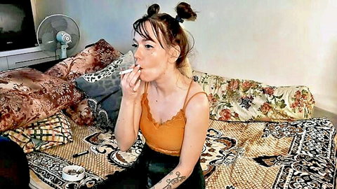 Sexy stepdaughter with space buns smoking seductively in orange tank top