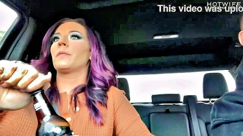 Purple-haired hotwife grips beer bottle to lips held by black hand in car backseat