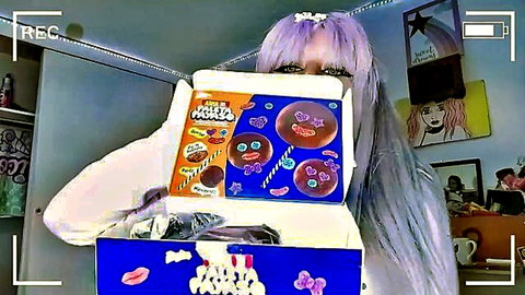 Cute purple-haired girl in sweater holding open Pop Tarts box smiling playfully in neon bedroom