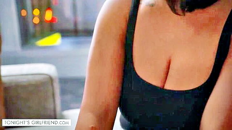 Busty brunette girlfriend in tight black top showing deep cleavage on hotel couch with city view