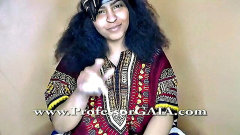 Smiling ebony webcam girl with curly hair pointing finger in red dashiki dress