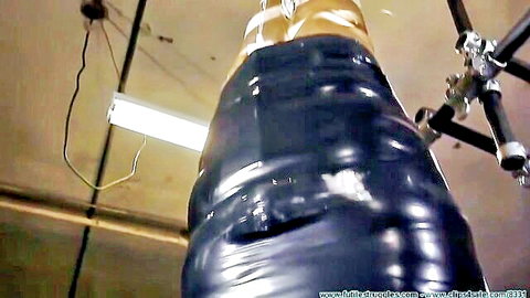 Shiny black latex mummified woman suspended upside down in extreme piledriver BDSM bondage