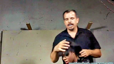 Latino man grips ebony woman's head by hair as she opens mouth wide in BDSM scene