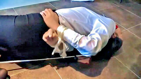 Bound Asian woman gagged in BDSM bondage scene on floor
