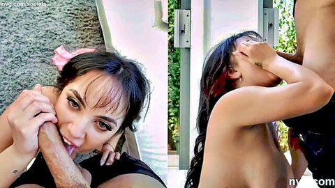 Brunette with pink ribbon slurps thick cock outdoors while topless girl with red streaks poses nearby