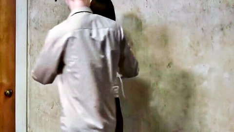 Man in shirt hand gagged from behind by dominant figure in BDSM domination scene