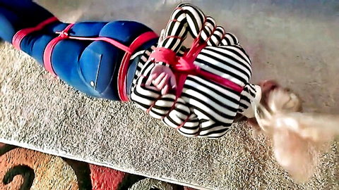 Blonde woman bound in tight jeans and striped shirt BDSM bondage scene