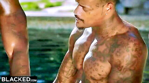 Muscular tattooed Black man with mustache glistening wet by pool in Blacked scene