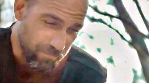 Intense bald bearded man in outdoor BDSM scene, close-up expression