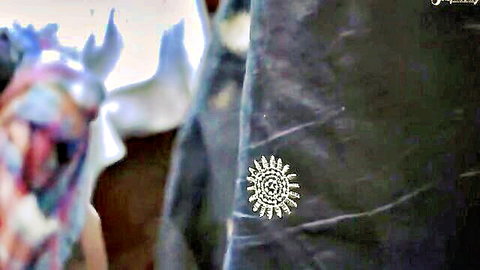 Shiny spiked sun brooch pinned on dark purple fabric closeup
