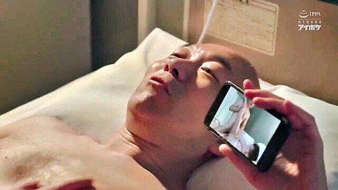 Shirtless bald mature Japanese man in hospital bed watching young East Asian porn on phone