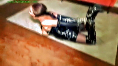 Bound brunette in shiny black latex catsuit restrained on floor in BDSM pose