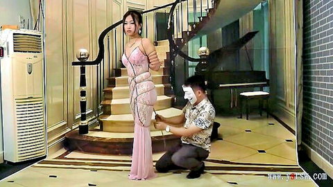 Chinese woman in pink long dress bound in ropes, BDSM bondage scene