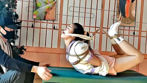 Asian woman in strict Chinese hogtie bondage, gagged and bound in ropes, skirt hiked up