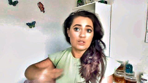Brunette woman in green top gesturing during close-up pussy waxing video