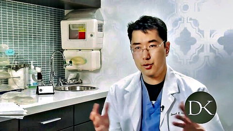 Asian doctor in lab coat discussing large breast augmentation