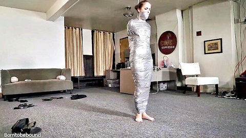 Bound woman mummified in shiny duct tape, gagged in solo BDSM scene